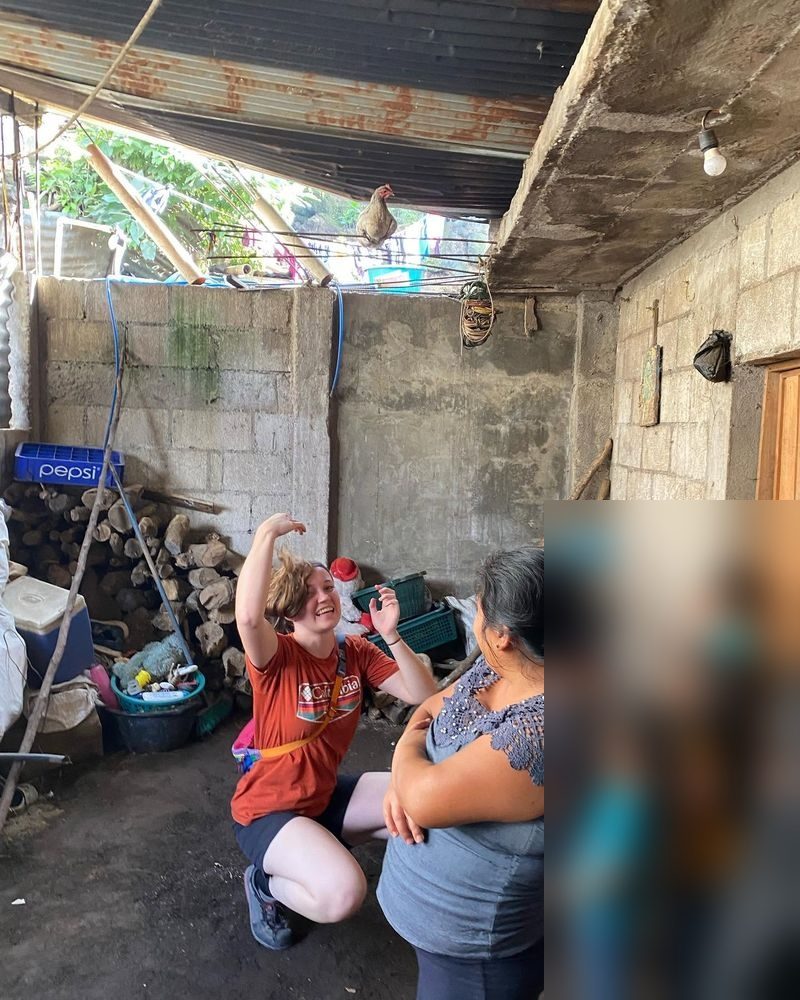 A volunteer laughing with a family inside their home in the Guatemalan highlands